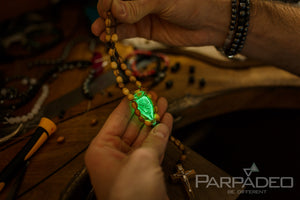 Religious inspired beaded olive wood car decoration features a hand blown glass amulet filled with Holy Water from the Jordan River. Handmade by PARPADEO - Israel.